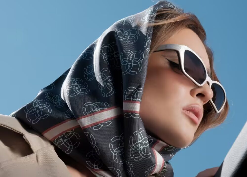 Elegant woman wearing a luxurious silk scarf with an intricate geometric pattern, styled as a headscarf.