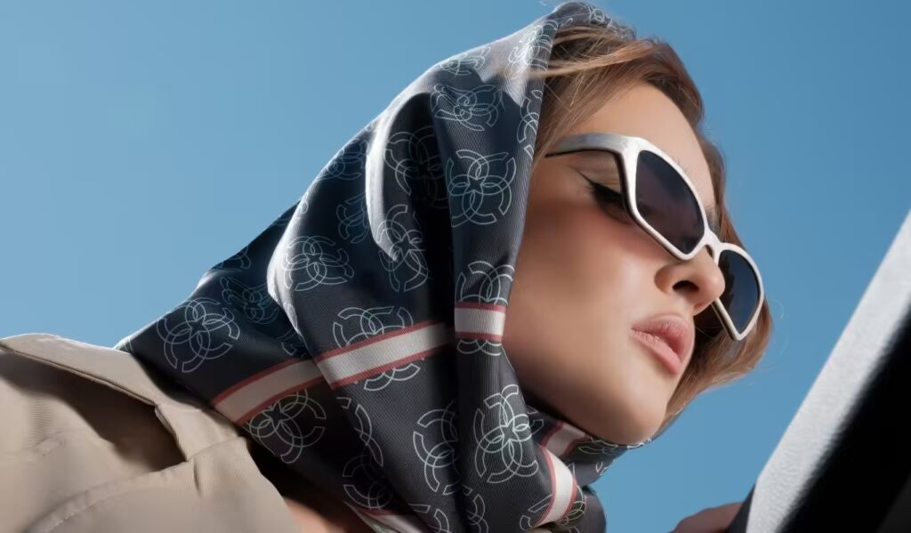 Elegant woman wearing a luxurious silk scarf with an intricate geometric pattern, styled as a headscarf.